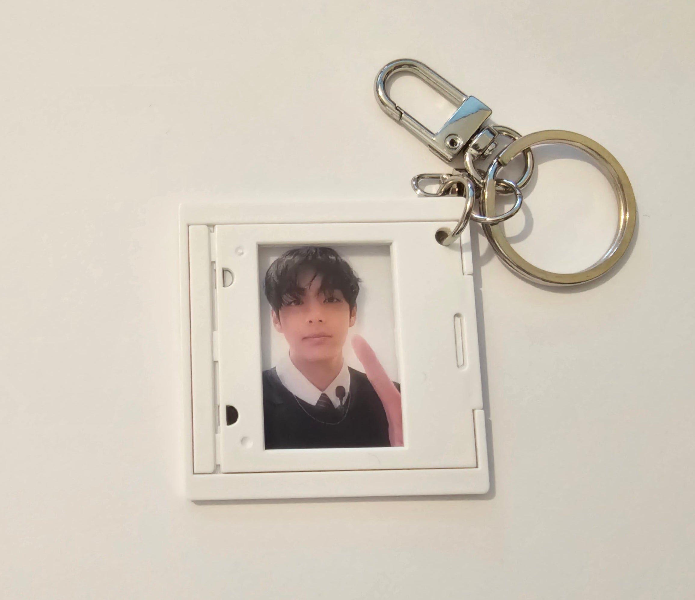 A white plastic ID photo holder keychain with a silver metal clasp and split ring, featuring a printed photo of a young man inside.